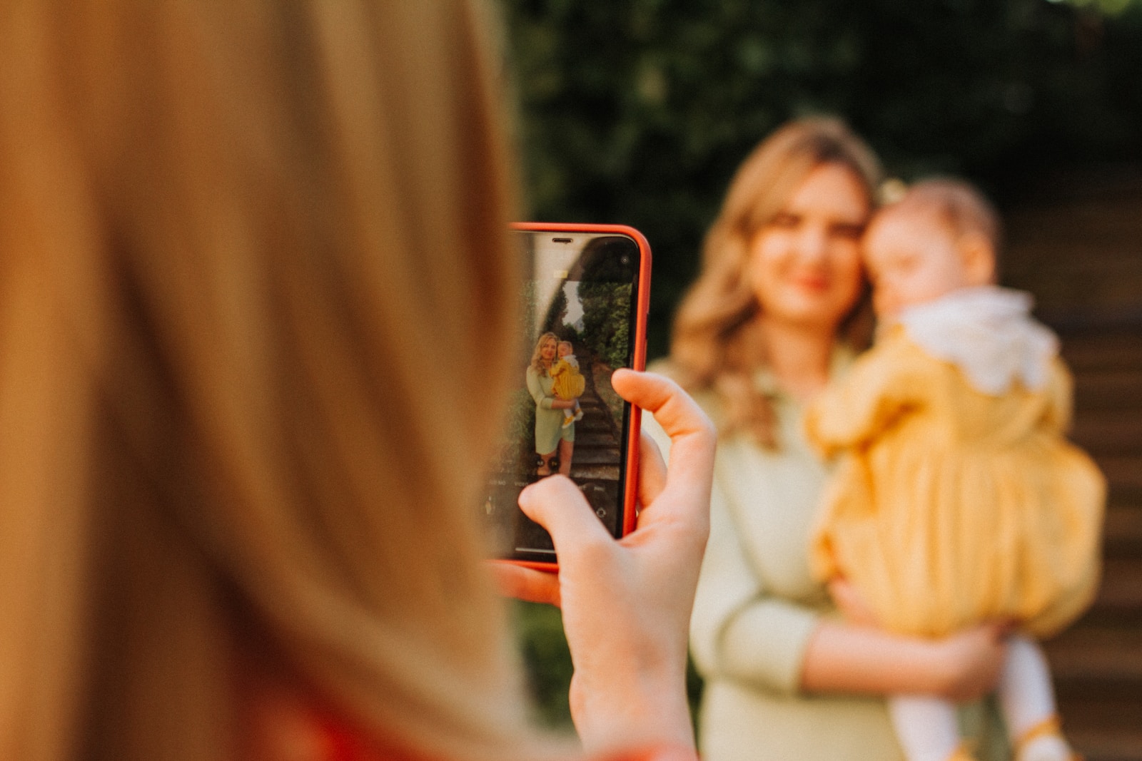 a woman taking a picture of a woman holding a baby